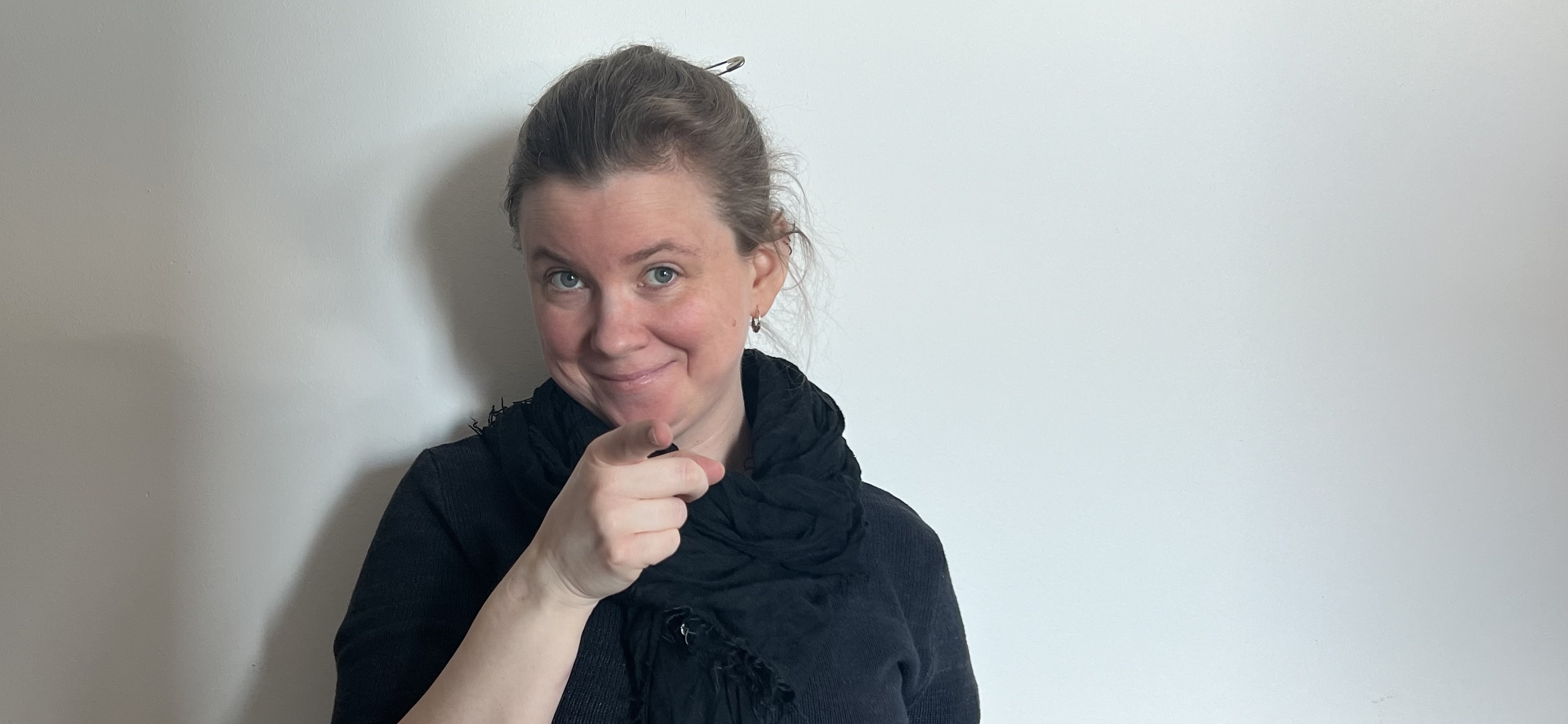 Image by Ester Daniel Ytterbrink Ester Daniel Ytterbrink on a white background, in black clothes, smiling and pointing into the camera.