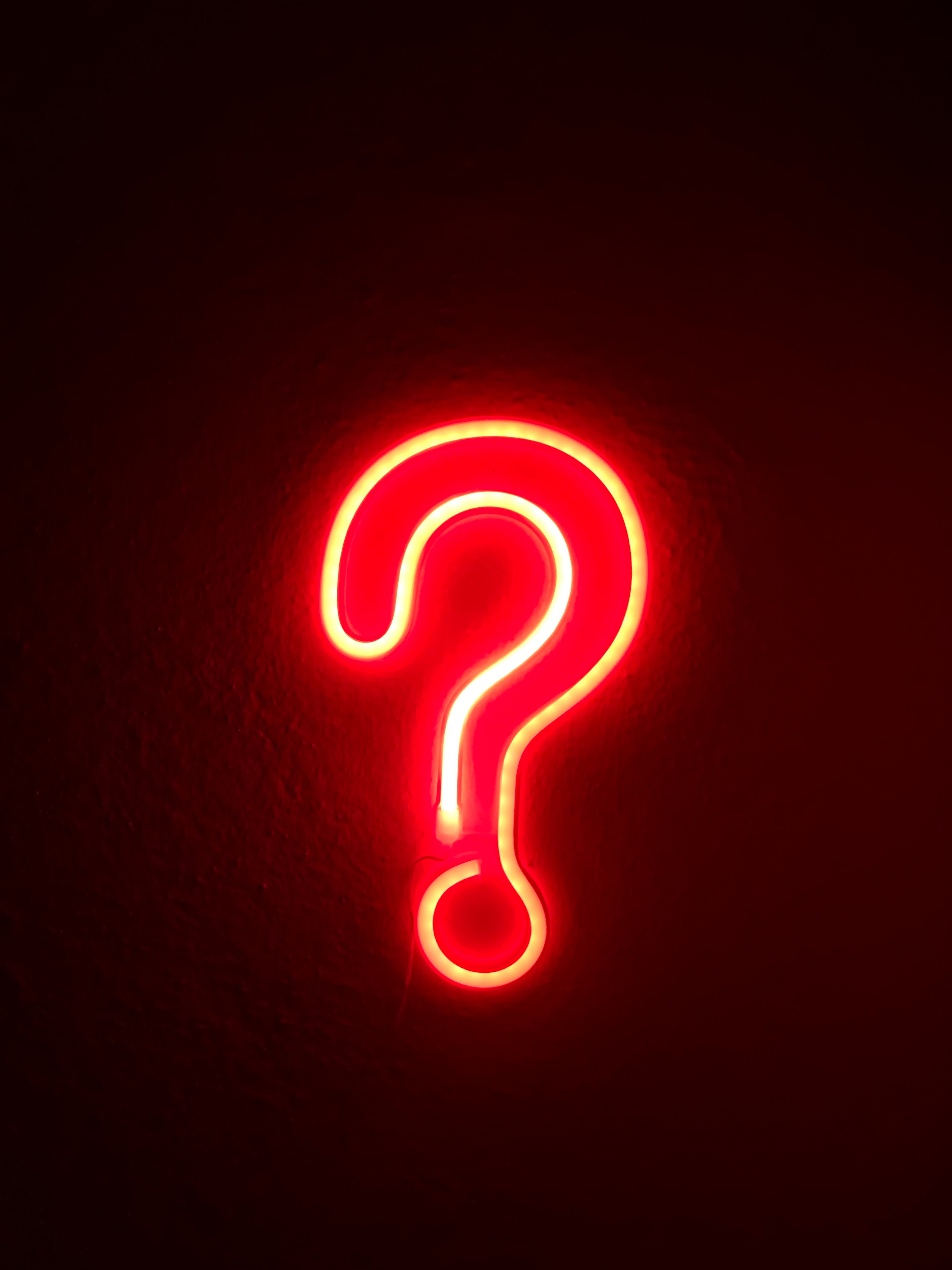 A red neon sign of a question-mark