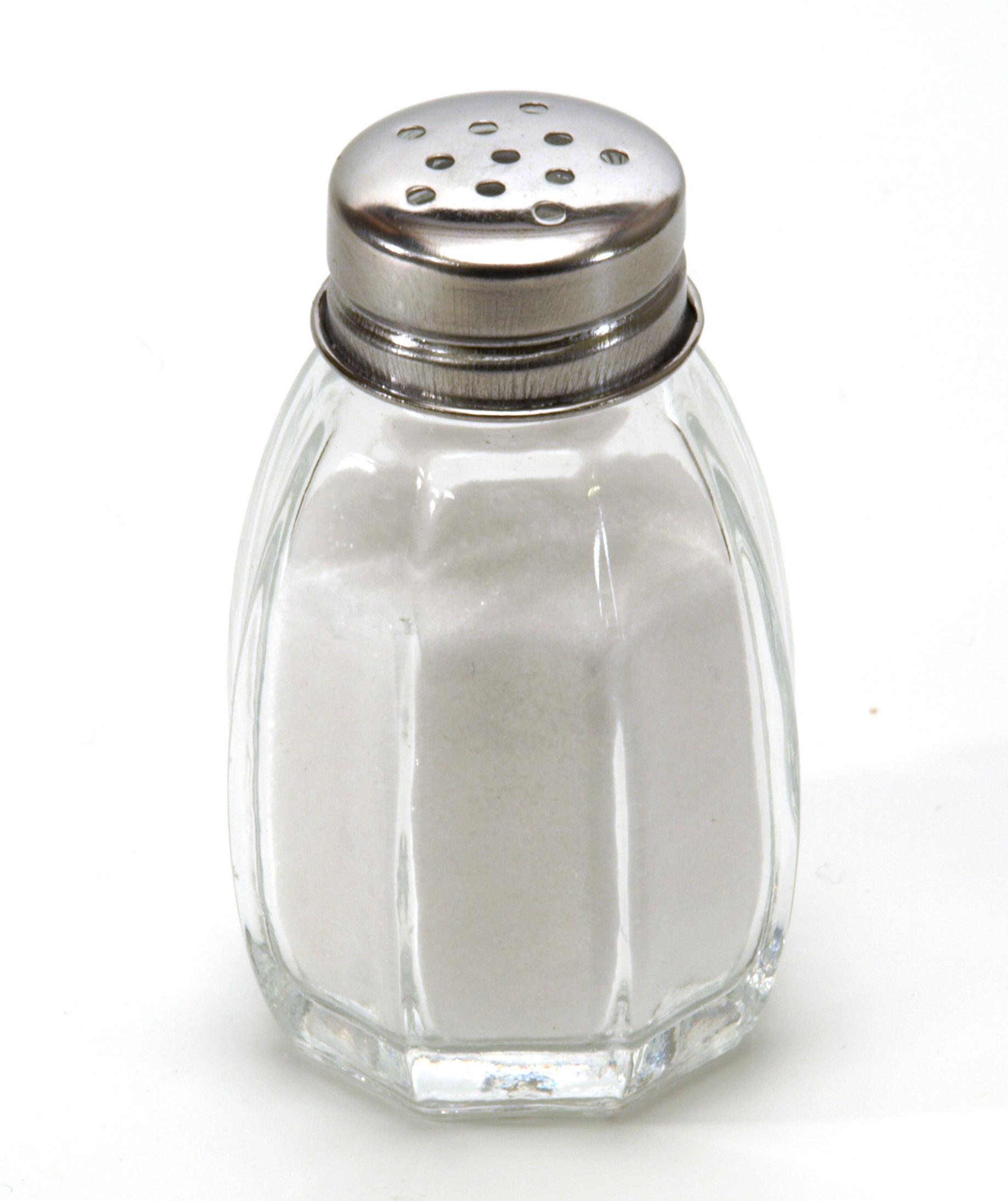 a glass salt shaker with a metal top photographed on a white background.